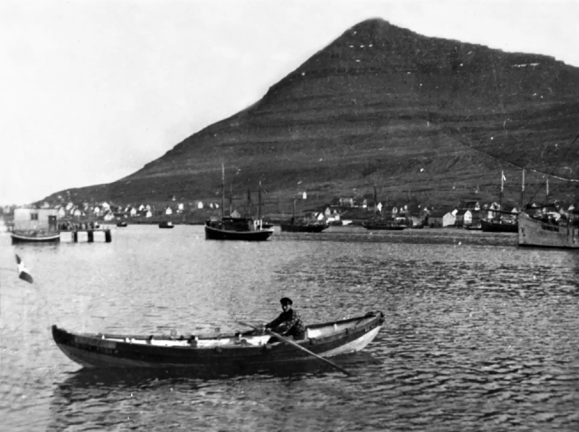 Óla Jákup Jacobsen, ferjumaður, í báti sínum. Hann fór at flyta fólk um vágna í 1935. Hetta er helst fyrsti bátur hansara. Mynd: Tjóðsavnið