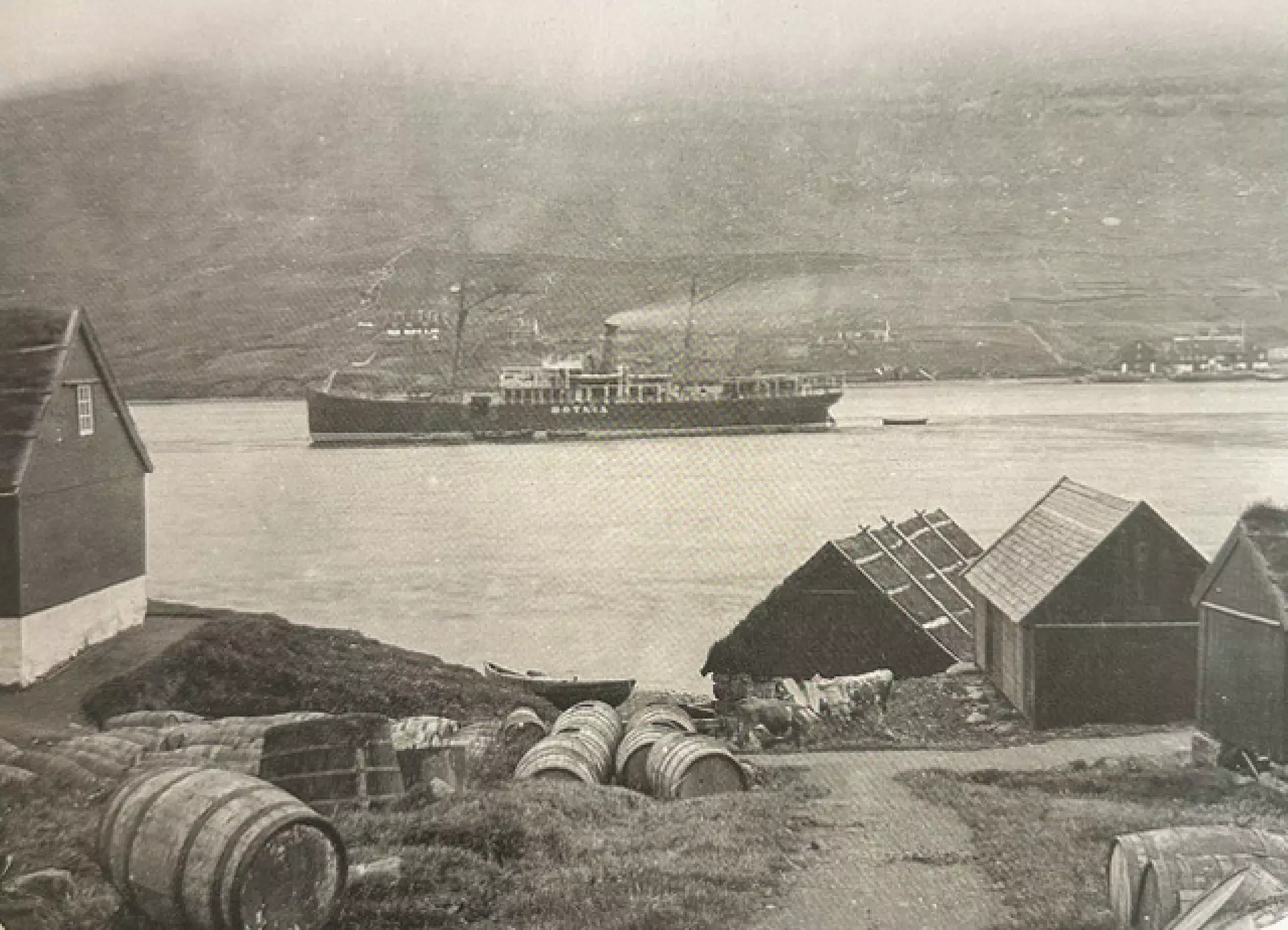 Jóhannus í Búðunum og Sigrid Súsanna giftust sama ár, sum hendan myndin varð tikin uttanfyrii Búðarnar, úti í gomlu Klaksvíkini. Myndin er úr bókini ‘Færøerne 1894 - en fotograf kommer forbi’ hjá Steffen Stuman Hansen og Kevin J. Edwards. Um myndina skriva teir: ‘Rundan um Vánna lógu í 1890’unum fleiri ella minni spjaddar búsetingar, harav tær fýra – Vágur, Gerðar, Uppsalir og Myrkjanoyri (Biskupstøð) – um hesa tíð vóru við at vaksa saman og gjørdust tað, ið bleiv til Klaksvík. Við fólkateljingini í 1890 vóru tilsamans 380 íbúgvar býttir á 64 hús í hesum fýra búsetingunum. Myndin er tikin frá vestursíðuni av vánni, umleið 100 metrar norðan fyri handilshúsini úti í Klaksvík. Hon vísir bústaðin (til vinstru) hjá Nickels Lützen (1843–1912), sum var komin úr Tórshavn í 1858, og sum í 1894 arbeiddi í handlinum. Úthúsini til høgru hoyrdu til stjóran Johan Christian Djurhuus (1835–1918), meðan neystið helst var ogn hjá handilsfyritøkuni. Á vánni sæst dampskipið Botnia. Har var eingin bryggja til so stórt skip, so ferðafólk og vørur máttu flytast í smáum bátum inn til handilsstaðið. Hinumegin fjørðin sæst handilhúsið á Stongunum, har fyrstu bygningarnir vórðu reistir av handilsmanninum Joen Peter Olsen í 1863.’