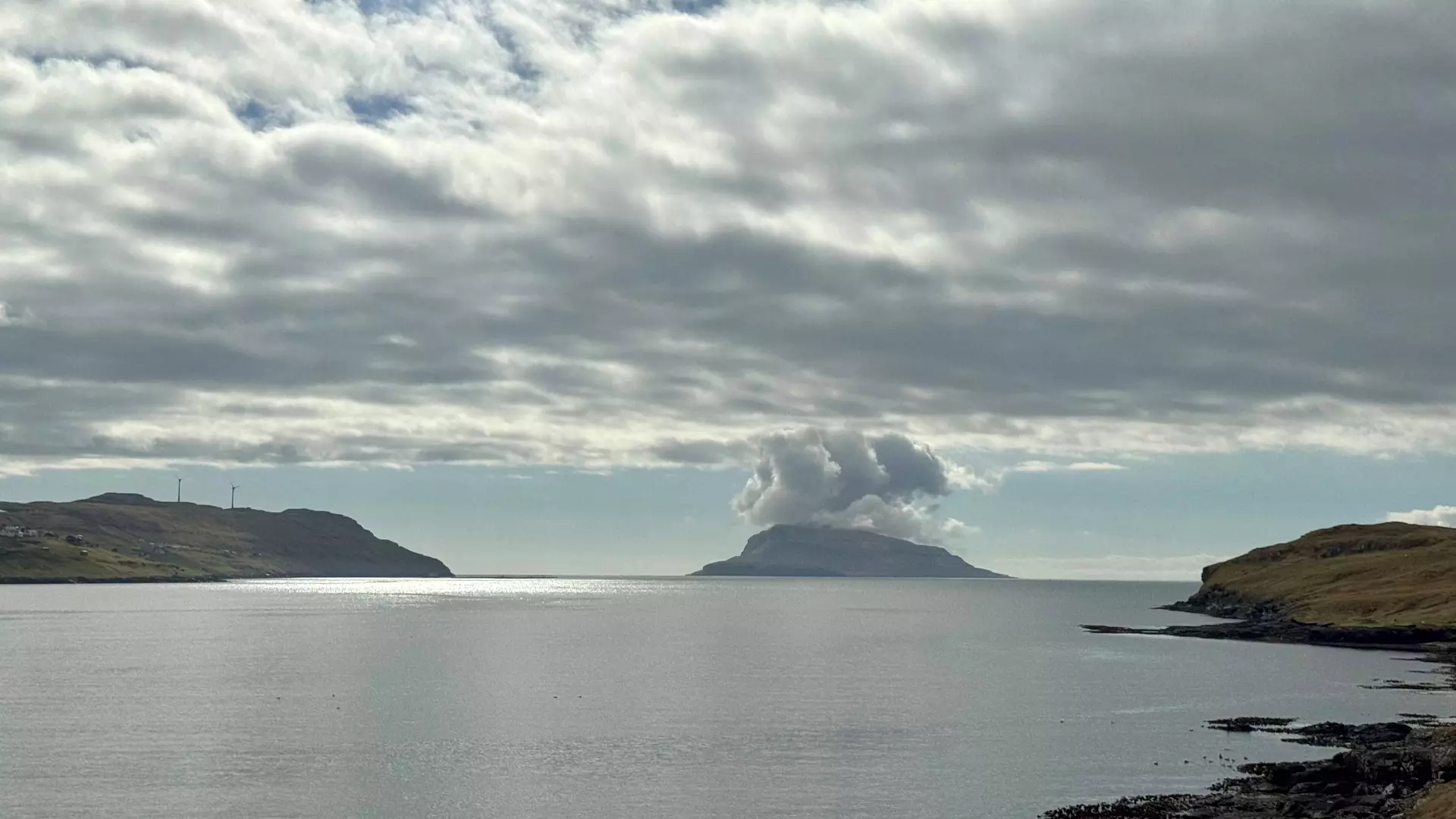 Seinastu 10 dagarnar í apríl lá eitt hátrýst yvir okkara leiðum. Nógvar løtur við stilli ella eitt kyld av ymsum ættum. Fyrrapartin 21. apríl var eitt lítið fleyr av eystri, og Nólsoyggin tvingaði luftina uppeftir. Eggjarklettur er 350 m høgur, og júst í tí hæddini tættaðist guvan til dropar. Tað sær út sum um eldur er í oynni. Mynd: Reidar Fríði Joensen.