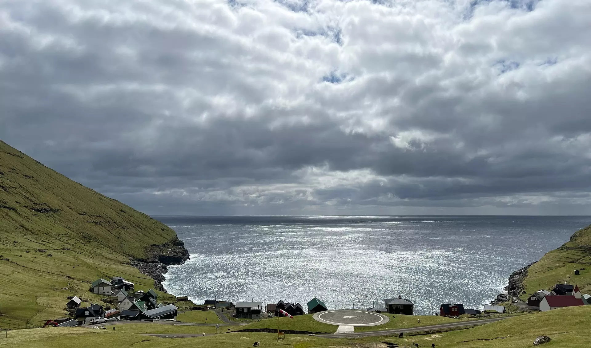 Beint fyri middag fríggjadagin 15. mai royndi sólin at bróta seg ígjøgnum tey tjúkku skýggini, sum hingu lágt sunnan fyri Hattarvík. Eitt lítið lot var av útnyrðingi, hitin var 5 stig. Tað kalda luftrakið hevði ligið í næstan 2 viku, og hægstu fjallatindarnir norðanfyri vóru enn hvítir. Mynd: Marin Gullaksen.